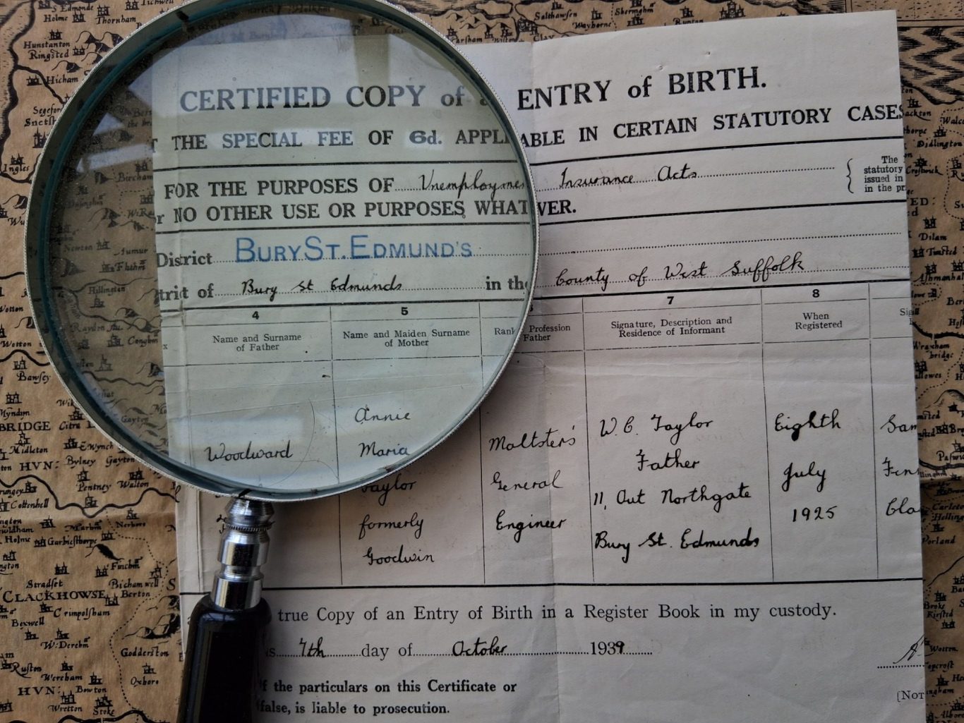 A Suffolk birth certificate with a magnifying glass on an old map.